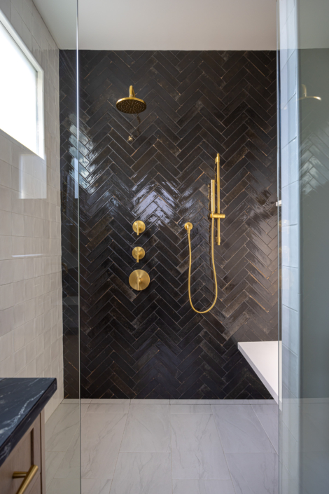 black glossy herringbone shower tile with brass hardware