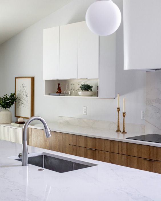 kitchen renovation in Raleigh NC with white flat panel upper cabinets with shelf below and a warm wood lower cabinet with white quartz and a sink in the island.