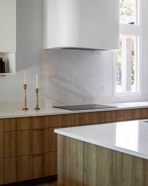 electric cook top with warm wood cabinet drawers beneath and smooth eased edge sheetrock modern vent hood.