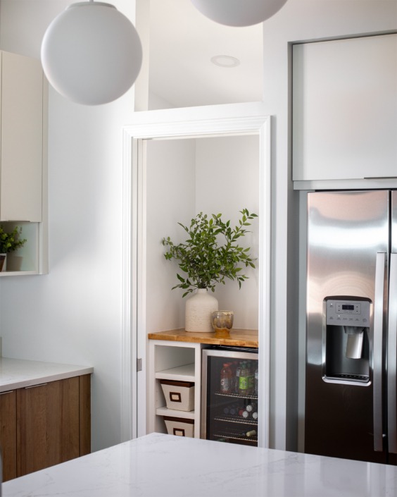 doorway looking into a walk in pantry from the kitchen with mini fridge under the cabinet. The door is a hidden pocket glass door