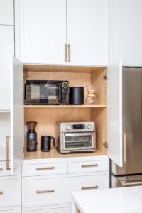 Appliance garage with white shaker push back cabinet doors, brass hardware, and concealed storage for a microwave, toaster oven, and coffee station.