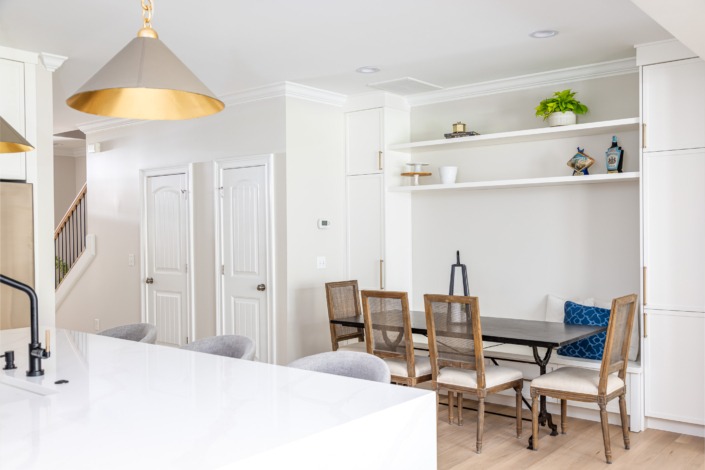 Open dining nook with built-in bench seating, custom floating shelves, and seamless flow into the adjacent living space, finished with light wood flooring and clean transitional details.