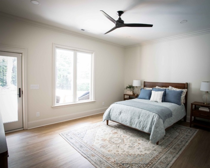 Wakefield_IMG_0007 Charming basement guest bedroom with a large window, warm wood flooring, neutral finishes, and a modern ceiling fan.