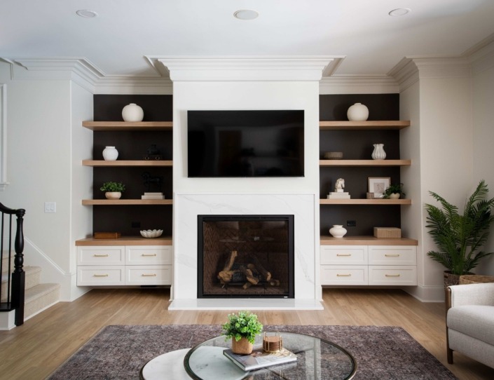 Wakefield_IMG_0009 (2) High end basement living room with a modern fireplace, custom white built-ins, warm wood floating shelves, and integrated lighting.