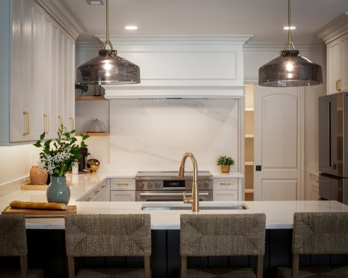Wakefield_IMG_0012 Basement remodel kitchen featuring white cabinetry, quartz countertops, open shelving, bar seating, and oversized metal pendant lights.