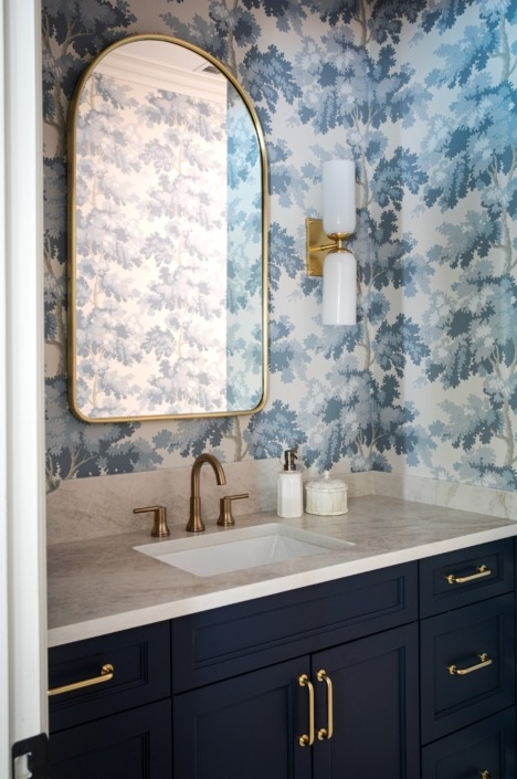 Wakefield_IMG_0020 (2) Charming basement powder room with a dark blue vanity, brass fixtures, white quartz countertop, and whimsical blue botanical wallpaper.