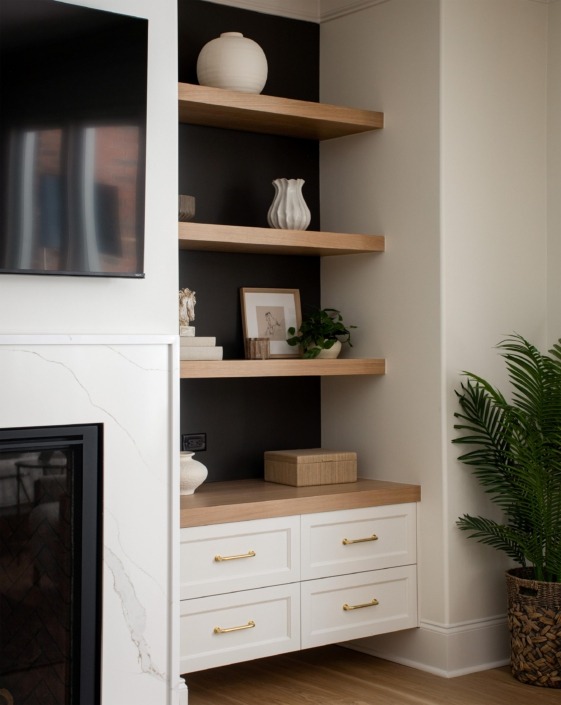 Wakefield_IMG_0022 Custom basement fireplace wall in Wake Forest, NC with white built-in cabinetry, warm wood floating shelves, integrated lighting, and modern decor.