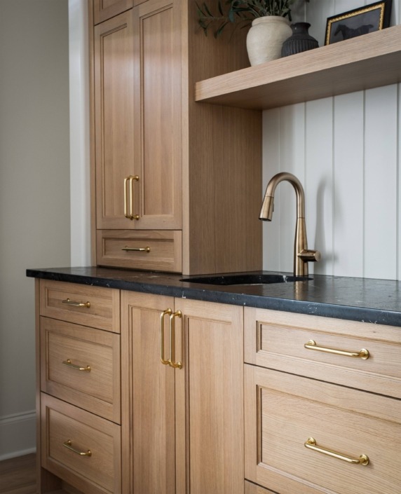 Wakefield_IMG_0025 Custom basement kitchenette with natural wood cabinetry, quartz countertops, brass hardware, open shelving, and a small prep sink.