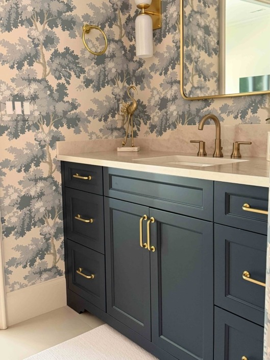 wakefieldIMG_1450 Dark blue bathroom vanity with brass hardware, white countertop, and botanical wallpaper.